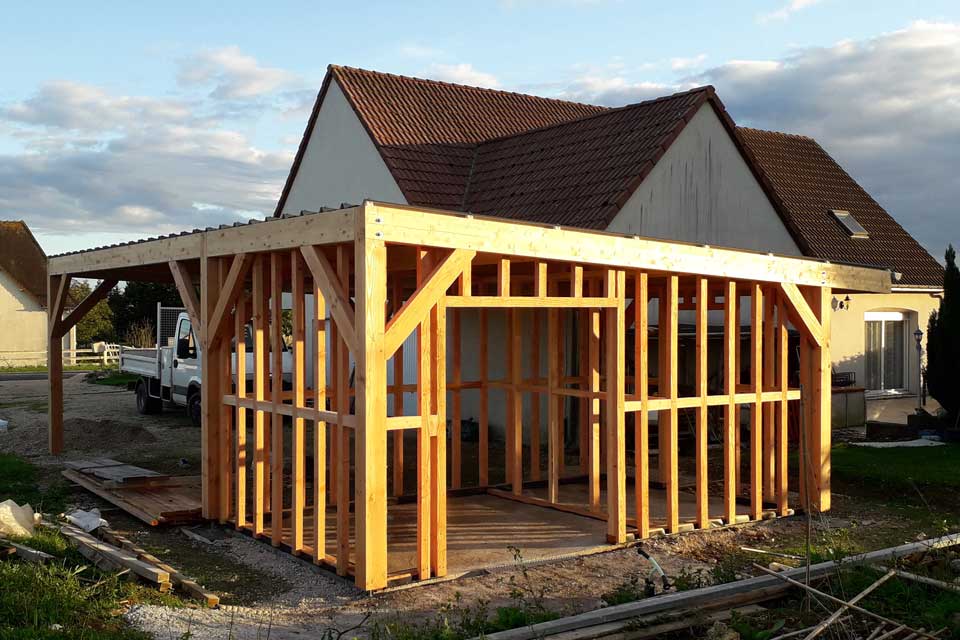 Structure en bois d'un abri de jardin intégré à un carport double.